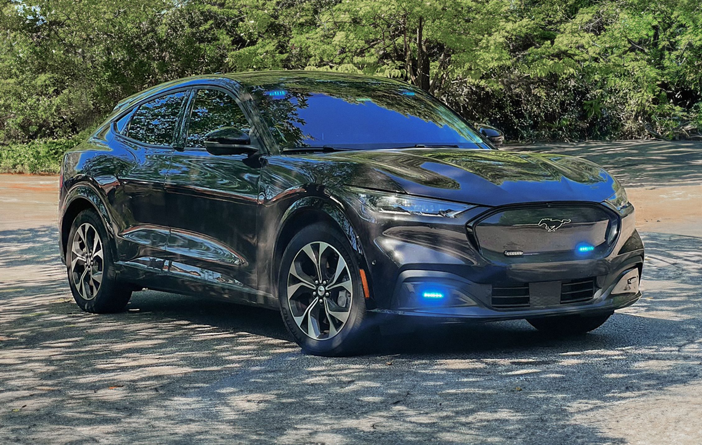 A Mustang® Mach-E® SUV with its lights on parked in the shade 