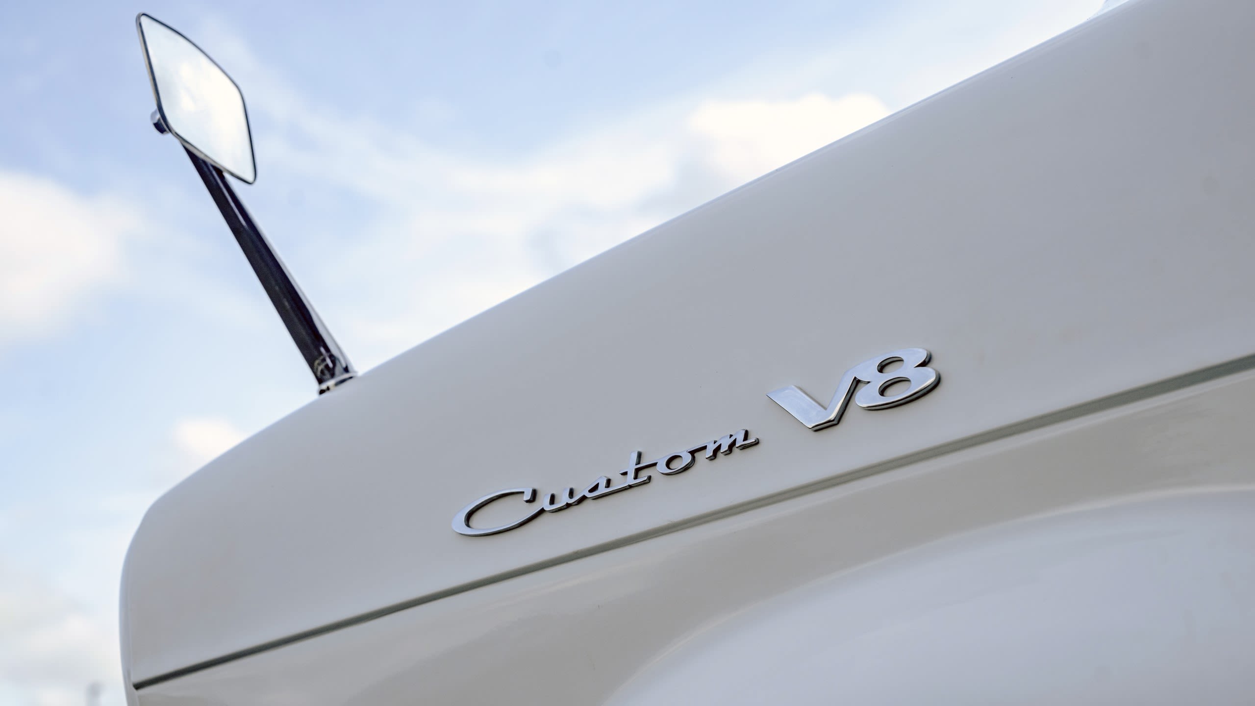 Ford Custom V8 badges on the front wing of Supervan 1 with a blue sky in the background
